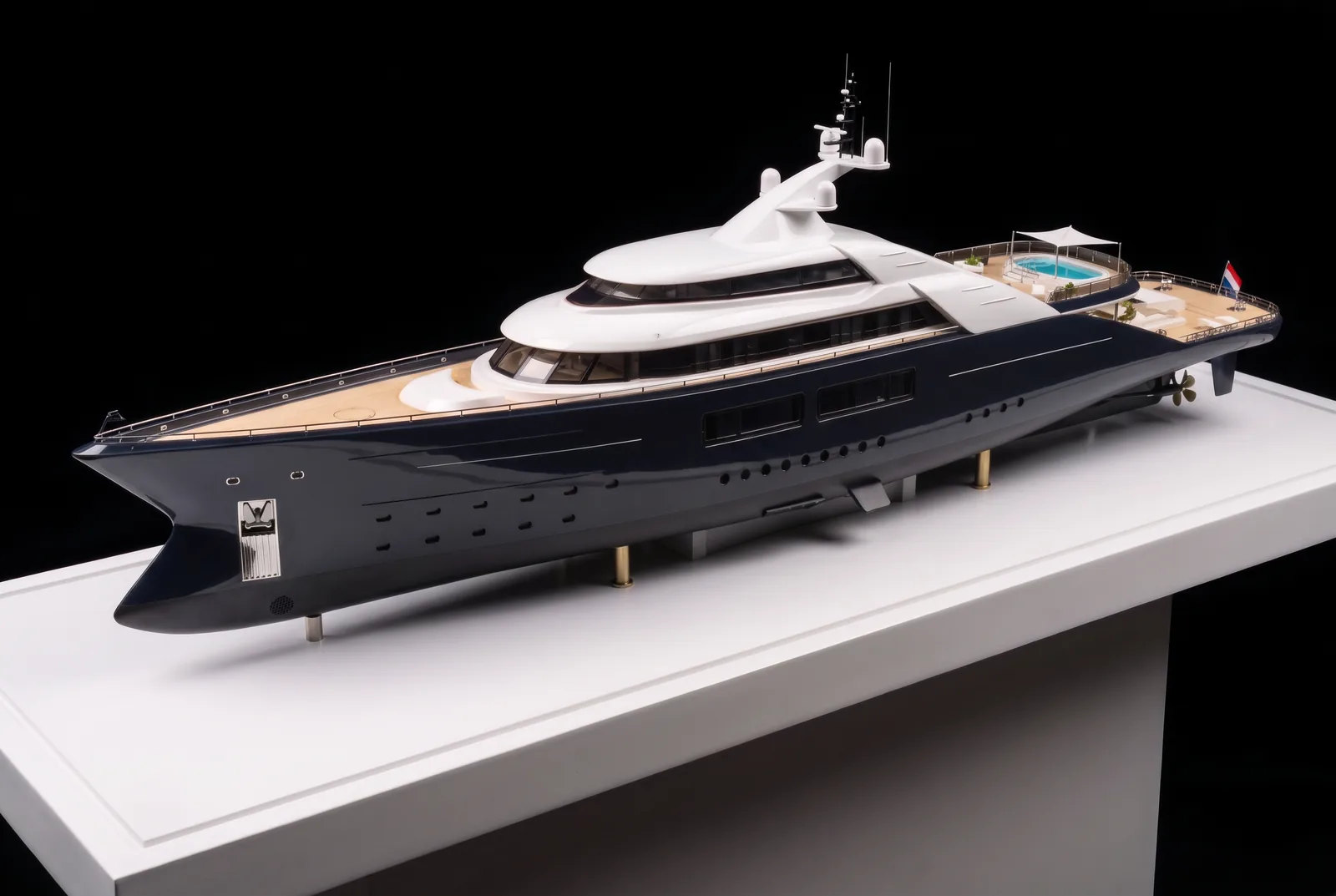 Superyacht scale model with navy hull and teak decks on a white display base